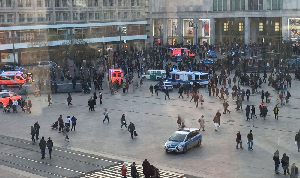 Picture taken through a window shows people standing around police cars and ambulances at Alexanderplatz square in Berlin on Thursday. — AFP
