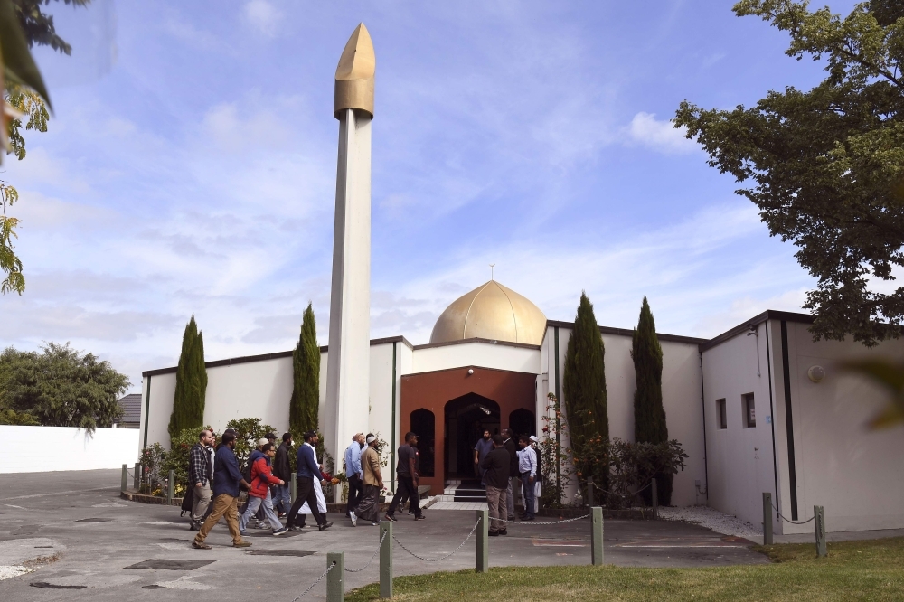 Members of the local Muslim community wait to enter the Al Noor Mosque as it is reopened in Christchurch, Saturday. — AFP