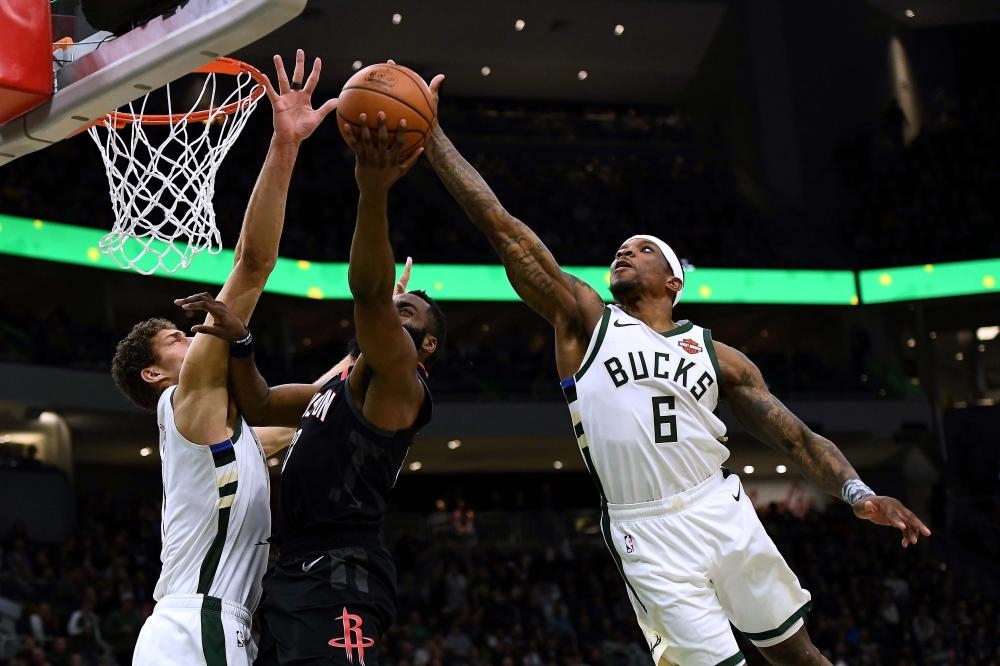 Eric Bledsoe of the Milwaukee Bucks blocks a shot by James Harden of the Houston Rockets during their NBA game at Fiserv Forum in Milwaukee Tuesday. — AFP