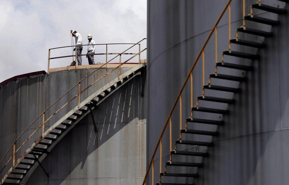 Employees perform quality inspections on top of a tank at the Ceylon Petroleum Corporation's (CPC) Sapugaskanda Oil Refinery in Colombo, Sri Lanka, in this file photo. — Reuters