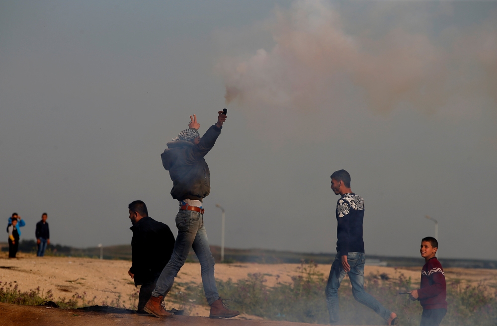 A Palestinian demonstrator holds a tear gas canister fired by Israeli troops during a protest at the Israeli-Gaza border fence, east of Gaza City, on Friday. — Reuters