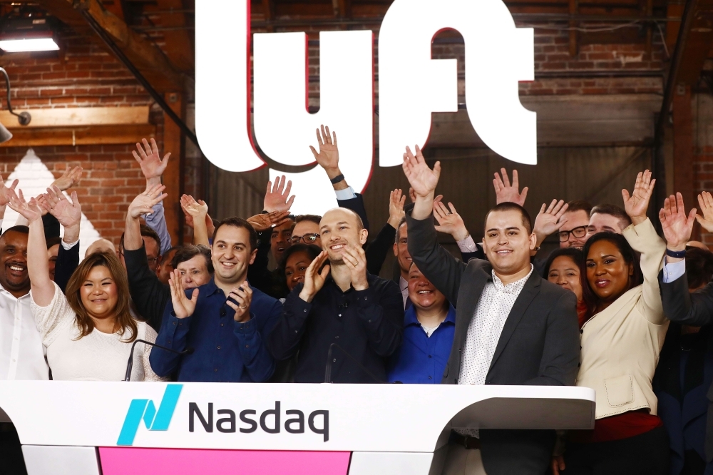 Lyft CEO Logan Green (C) and President John Zimmer (LEFT C) applaud during the Nasdaq opening bell ceremony celebrating the company's initial public offering (IPO) on Friday in Los Angeles, California. The ride hailing app company's shares were initially priced at $72. — AFP