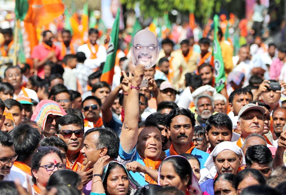 


A supporter holds a mask of Amit Shah, president of India’s ruling Bharatiya Janata Party (BJP), during a road show by Shah before filing his nomination papers for the general election, in Ahmedabad, on Saturday. — Reuters