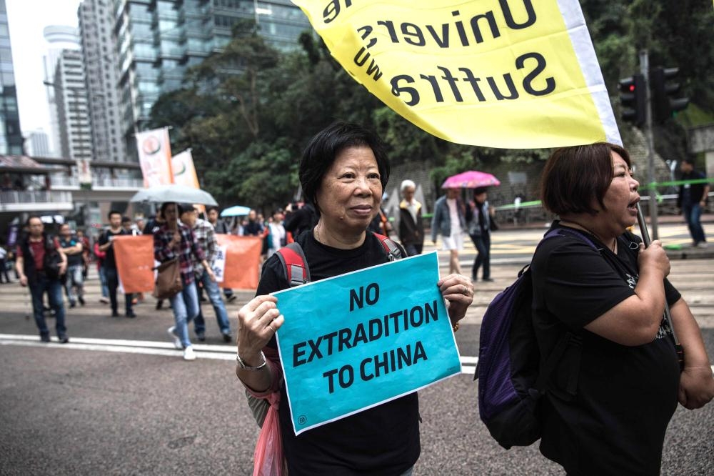 Protesters march along a street during a rally in Hong Kong on March 31, 2019 to protest against the government's plans to approve extraditions with mainland China, Taiwan and Macau.  Critics fear any extradition agreement could leave both business figures and dissidents in Hong Kong vulnerable to China's politicised courts, fatally undermining a business hub that has thrived off its reputation for a transparent and independent judiciary. / AFP / Dale DE LA REY
