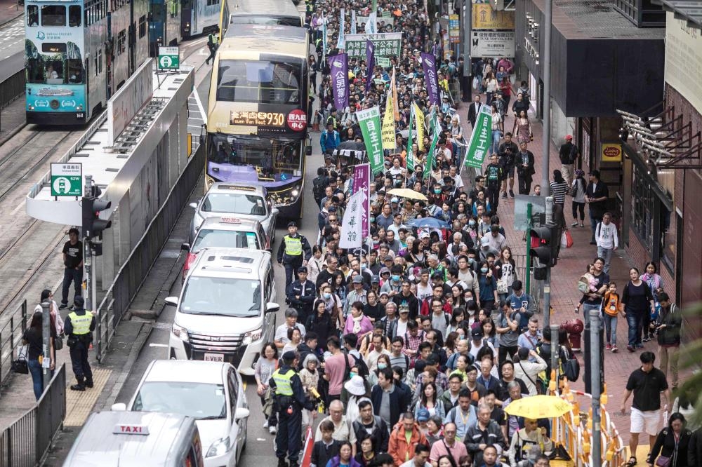 Protesters march along a street during a rally in Hong Kong on March 31, 2019 to protest against the government's plans to approve extraditions with mainland China, Taiwan and Macau.  Critics fear any extradition agreement could leave both business figures and dissidents in Hong Kong vulnerable to China's politicised courts, fatally undermining a business hub that has thrived off its reputation for a transparent and independent judiciary. / AFP / Dale DE LA REY
