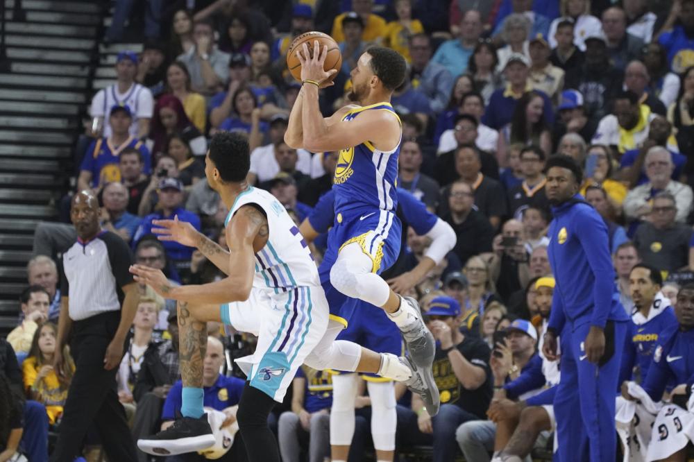 Golden State Warriors’ guard Stephen Curry shoots the basketball against Charlotte Hornets’ guard Jeremy Lamb during their NBA game at Oracle Arena Sunday. — Reuters