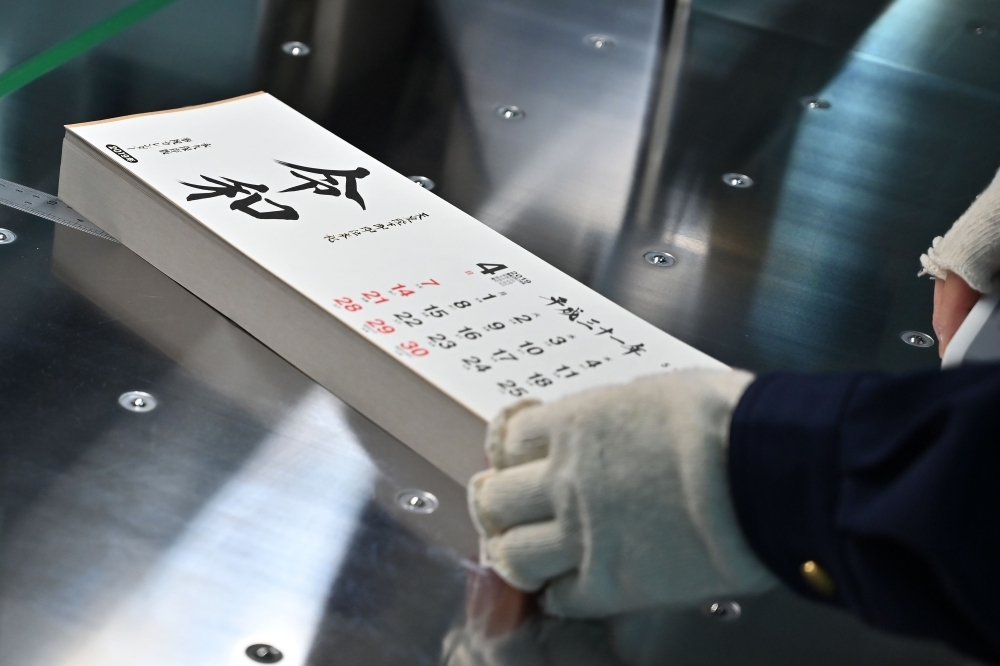 A Todan employee cuts sheets of a calendar bearing Japan’s next imperial era name “Reiwa” at a production plant in Ibaraki on Monday. — AFP