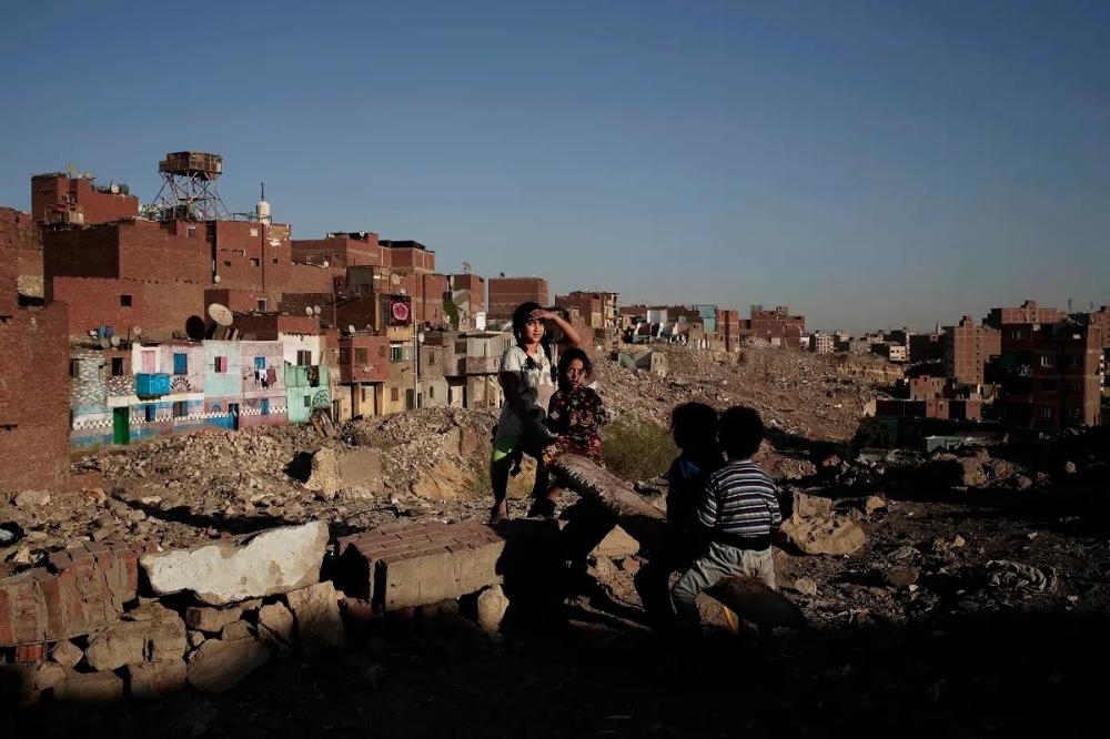 Children play on a makeshift see-saw made out of a tree trunk in slum area Ezbet Khairallah, Cairo, Egypt.

