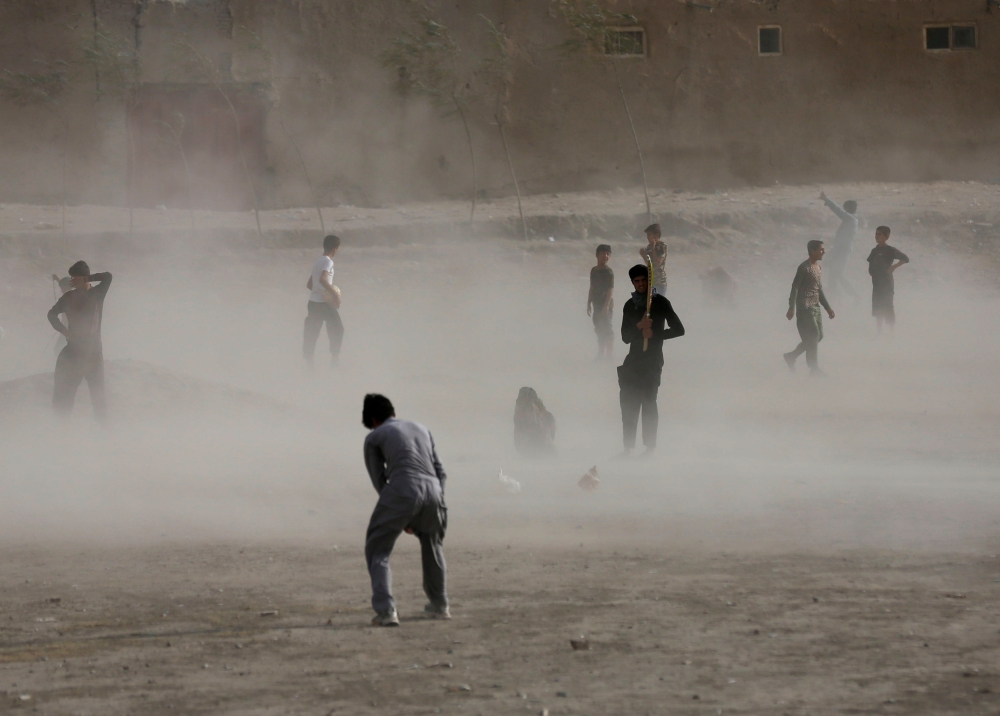 Afghan boy wait for a brief dust storm to pass while playing cricket in Kabul in this Oct. 7, 2016 file photo. — Reuters