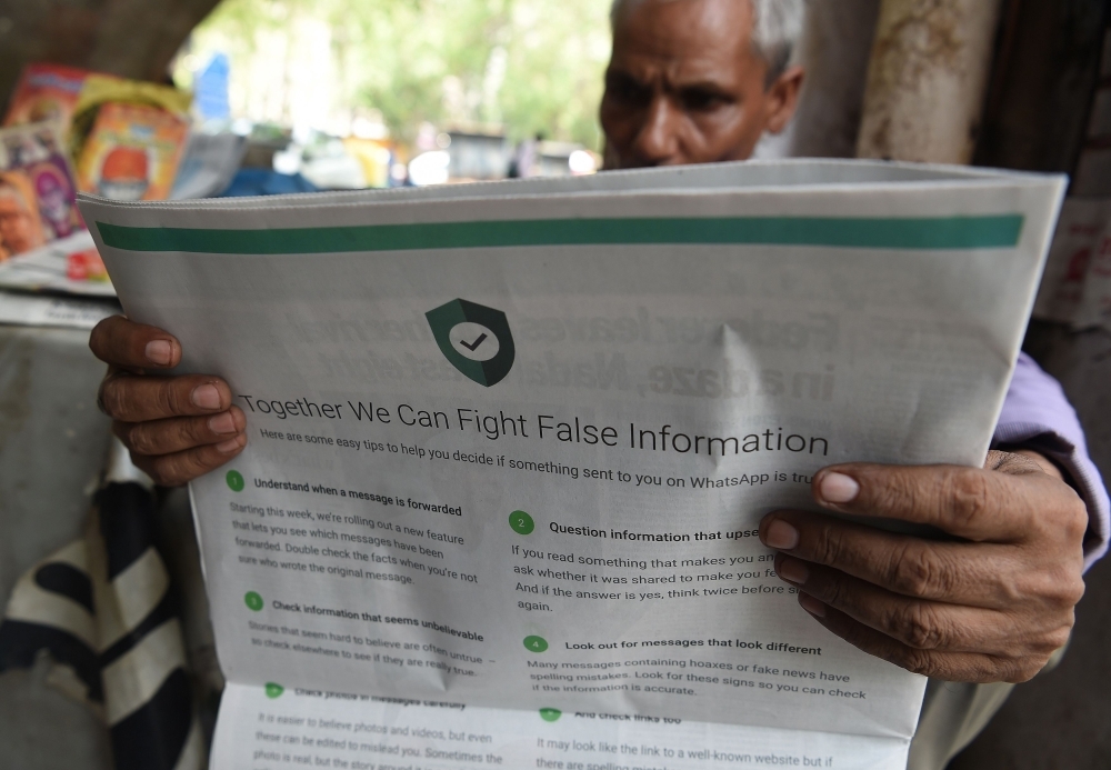 An Indian newspaper vendor reads a newspaper with a full back page advertisement from WhatsApp intended to counter fake information in New Delhi in this July 10, 2018 file photo. — AFP