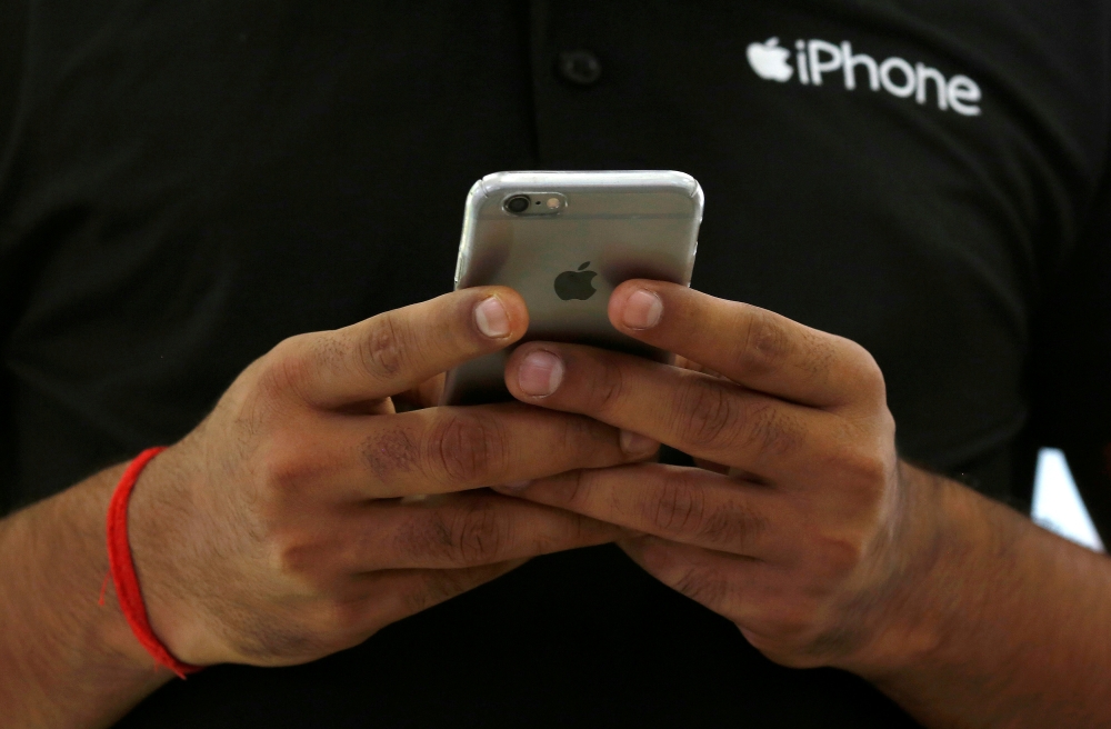 File photo shows a salesman using his iPhone at a mobile phone store in New Delhi, India. — Reuters