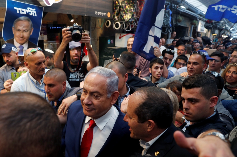 


Israeli Prime Minister Benjamin Netanyahu walks next to Likud party candidate, Nir Barkat as they visit Mahane Yehuda Market in occupied Jerusalem on Monday, a day ahead of Israeli national elections. — AFP 