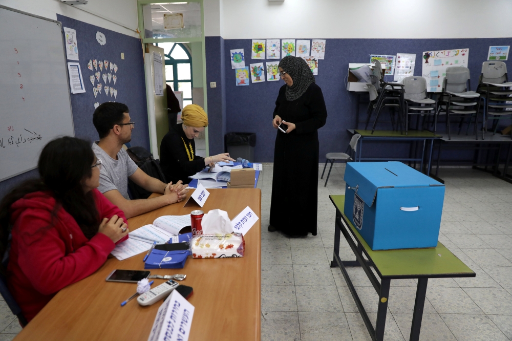 


An Israeli-Arab woman prepares to cast her ballot as Israelis vote in a parliamentary election, at a polling station in Umm Al-Fahm, Tuesday. — Reuters