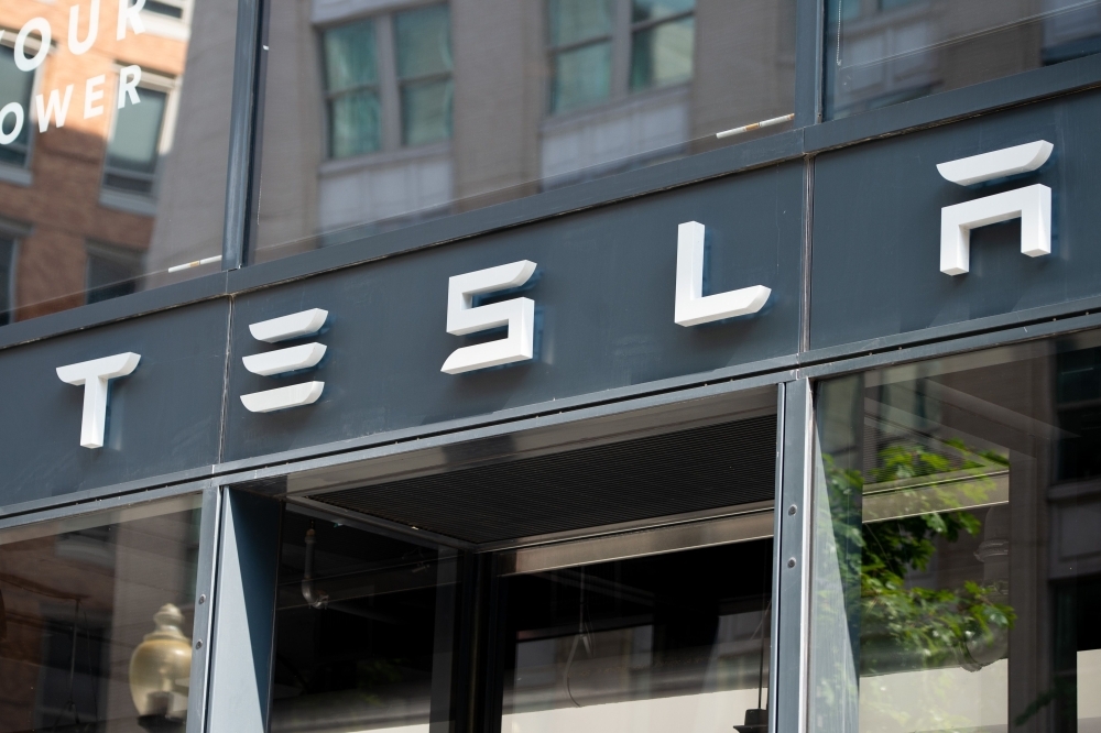 In this file photo the Tesla logo is seen outside of their showroom in Washington, DC. Shares of Tesla fell on April 11, 2019 following a report the electric car company and electronics giant Panasonic are suspending plans to expand a battery plant due to weak demand for the vehicles. — AFP