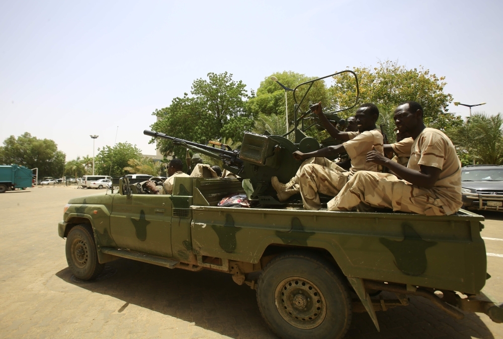 Members of the Sudanese military sit atop a gun-mounted vehicle as they guard the building housing the defence ministry in the capital Khartoum on Friday. — AFP