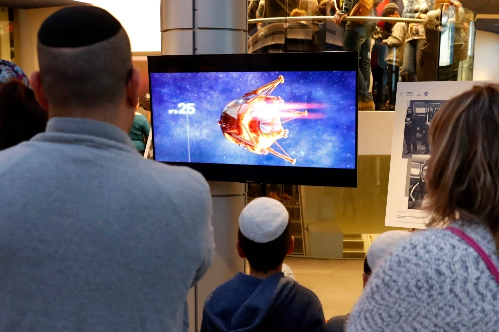 People watch a screen showing explanations of the landing of Israeli spacecraft, Beresheet’s, at the Planetaya Planetarium in the Israeli city of Netanya, on Thursday before it crashed during the landing. — AFP