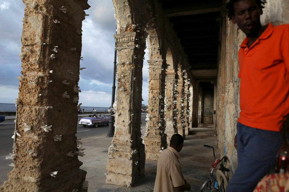 People stand near colonnades decorated with papers by Cuban artist Elio Jesus Fonseca, during the 13th Havana Biennial, in Havana, Cuba. — Reuters