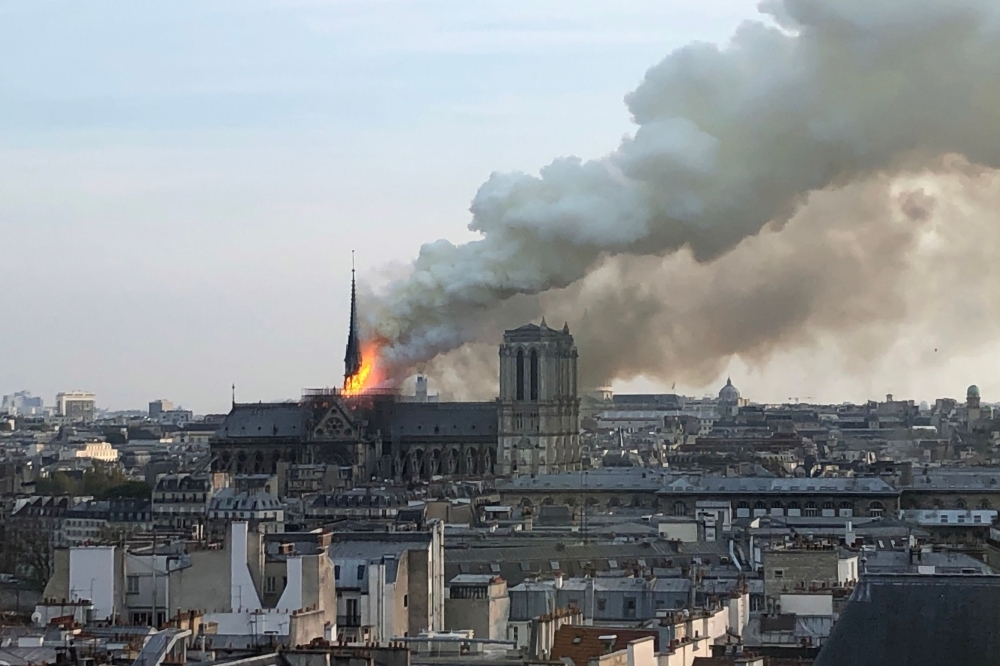  Flames and smoke billow from the roof at Notre-Dame Cathedral in Paris on Monday. — AFP