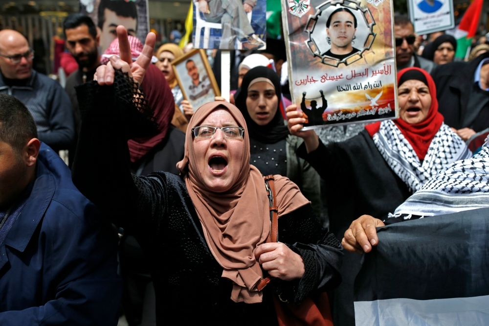 Palestinians chant slogans and gesture as they march with national flags and pictures of prisoners held in Israeli jails during a rally marking Palestinian Prisoners' Day in the West Bank city of Ramallah on Wednesday. — AFP