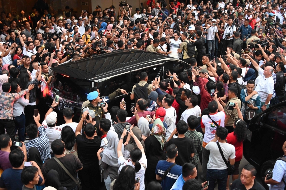 Supporters surround a vehicle carrying Indonesian President Joko Widodo after the country’s general election in Jakarta on Wednesday. — AFP