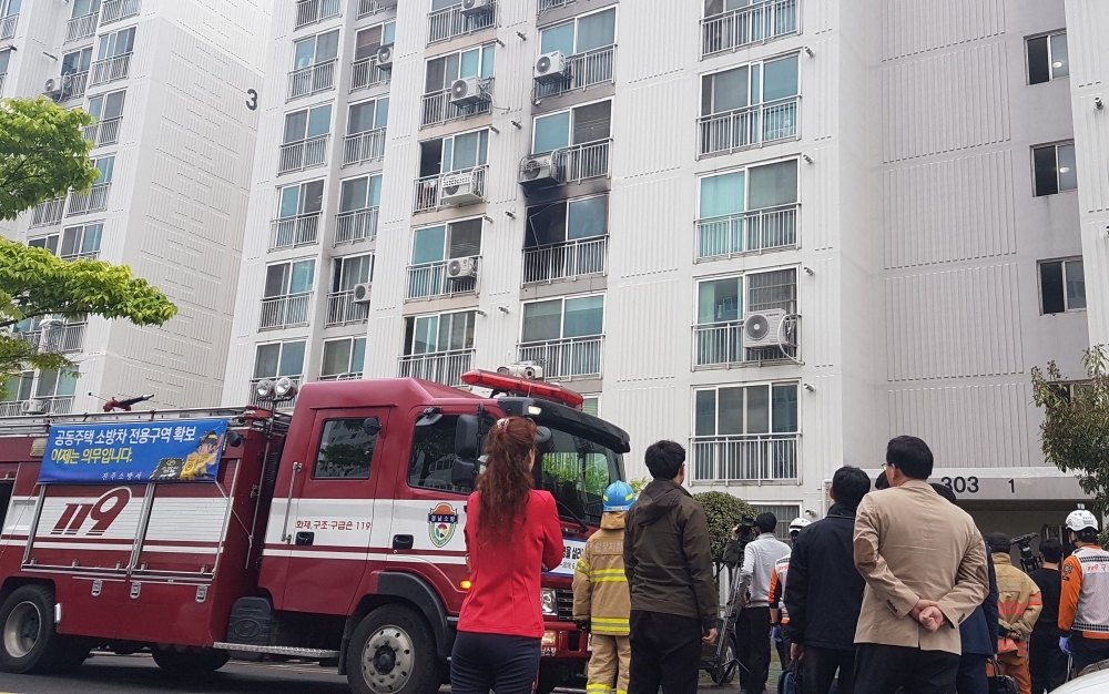 Firefighters and residents gather outside a fire-damaged apartment in the southern city of Jinju on Wednesday. — AFP