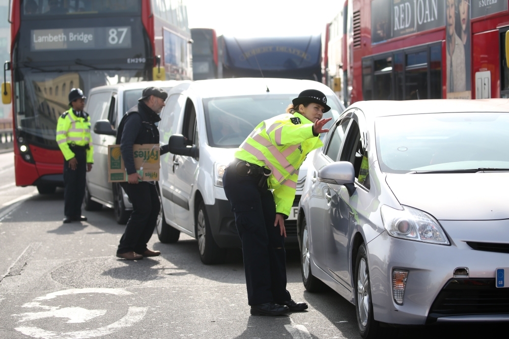 Police officers talk to motorists as climate change activists block traffic on Vauxhall Bridge in London on Thursday during the fourth day of an environmental protest by the Extinction Rebellion group. — AFP