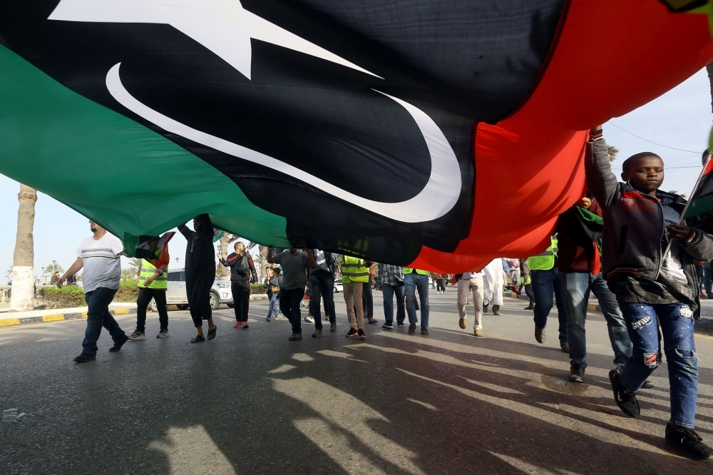 Libyans wave a giant national flag during a demonstration in the capital Tripoli's Martyrs Square. — AFP