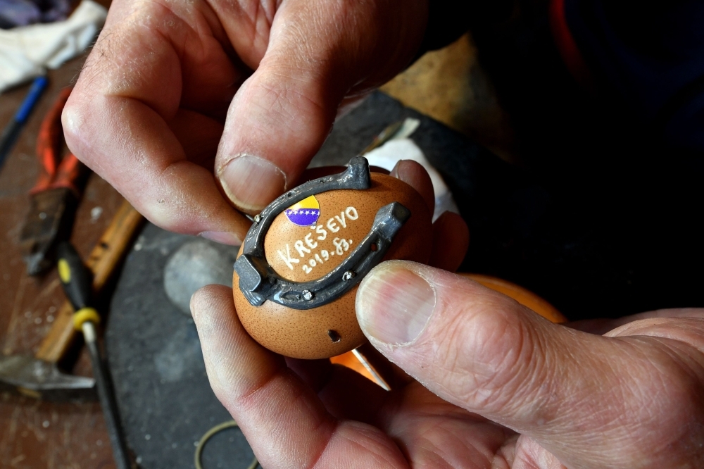 Stjepan Biletic, 71, handcrafts man from Central-Bosnian town of Kresevo, nails miniature horseshoe onto an egg, in his workshop. — AFP