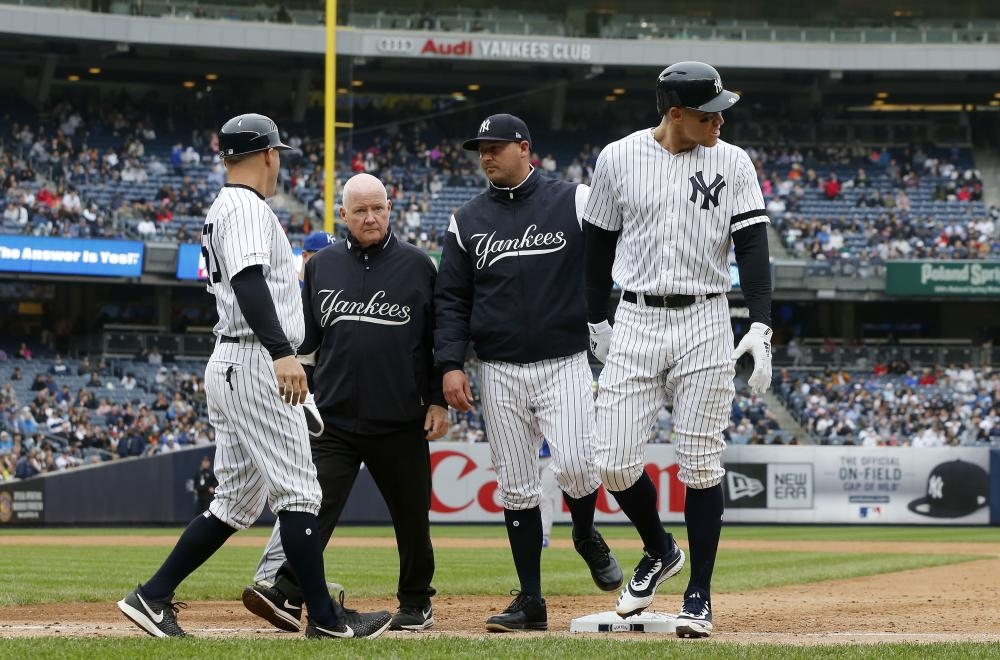 Aaron Judge (R) of the New York Yankees is checked on by bench coach Josh Bard, trainer Steve Donohue and first base coach Reggie Willits prior to leaving the game against the Kansas City Royals at Yankee Stadium in New York City Saturday. — AFP 