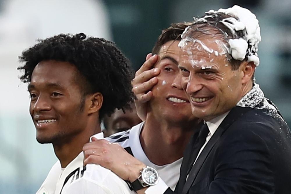 Juventus’ coach Massimiliano Allegri (R) embraces Cristiano Ronaldo, both with their head covered in foam, after Juventus secured its 8th consecutive Italian 2018/19 “Scudetto” Serie A championship, after winning the Italian Serie A match against Fiorentina at the Juventus Stadium in Turin Saturday. — AFP 