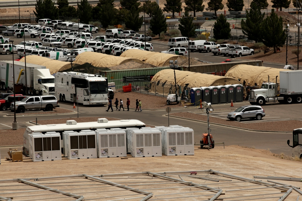 Migrant women are led by staff near an area where a temporary facility for processing migrants is being built at the US. Border Patrol headquarters in El Paso, Texas, on Monday. — Reuters