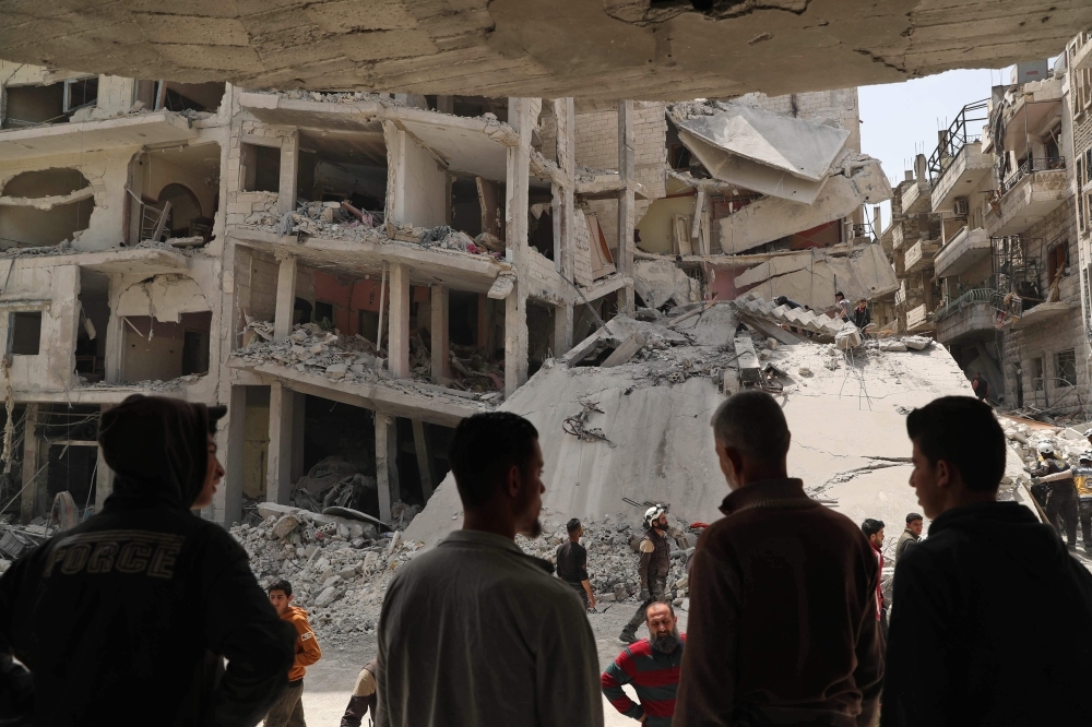 People watch as members of the Syrian Civil Defense search the rubble of a collapsed building following an explosion in the town of Jisr Al-Shughur, in the west of the mostly rebel-held Syrian province of Idlib, on Wednesday. — AFP