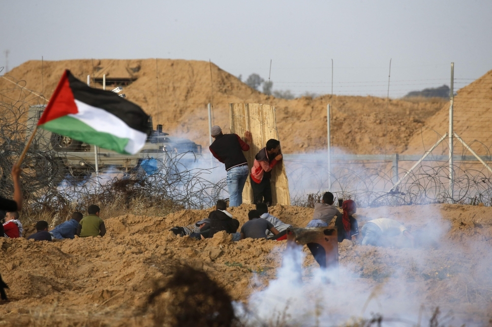 Palestinian protesters use a makeshift shield during a demonstration near the border with Israel, east of Khan Yunis in the southern Gaza Strip, on Friday. — AFP