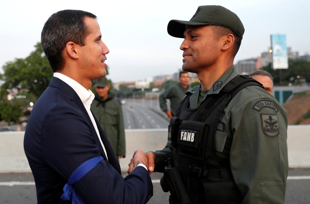 Venezuelan opposition leader Juan Guaido, who many nations have recognized as the country’s rightful interim ruler, shakes hands with a military member near the Generalisimo Francisco de Miranda Airbase “La Carlota,” in Caracas, Venezuela, on Tuesday. — Reuters