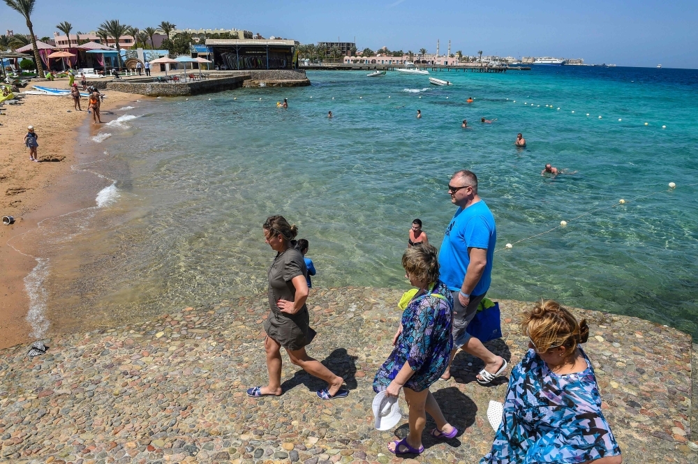 Tourists walk on a beach in Egypt's Red Sea resort town of Hurghada. In dazzling turquoise waters off Egypt's Red Sea coast, scuba divers swim among delicate pink jellyfish and admire coral — but the rebounding tourism sector is worrisome for the fragile marine ecosystem. — AFP

