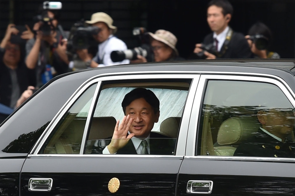 Japan’s new Emperor Naruhito, center, waves to well-wishers as he arrives back at the Imperial Palace in Tokyo on Wednesday. — AFP