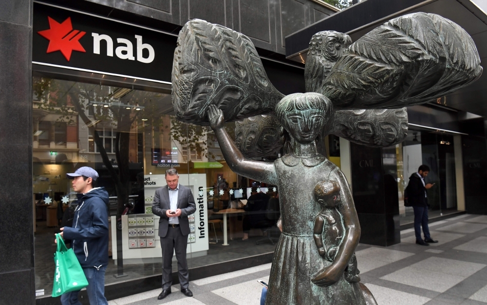 People walk past a National Australia Bank (NAB) branch in Melbourne on Thursday, as the NAB revealed that in the last six months it had put aside $368 million for 