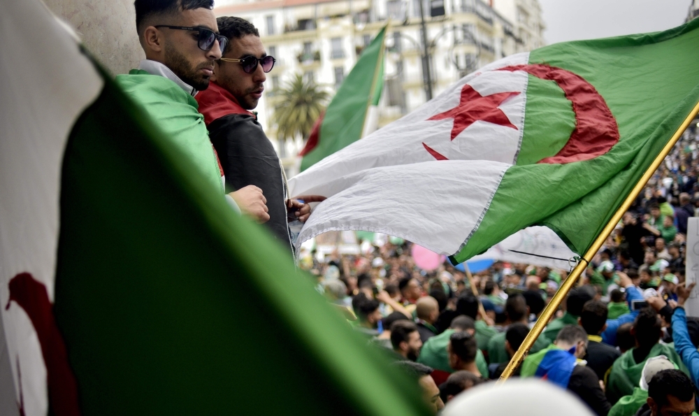  protesters wave a national flag as they take part in a demonstration in the capital Algiers on Friday. — AFP