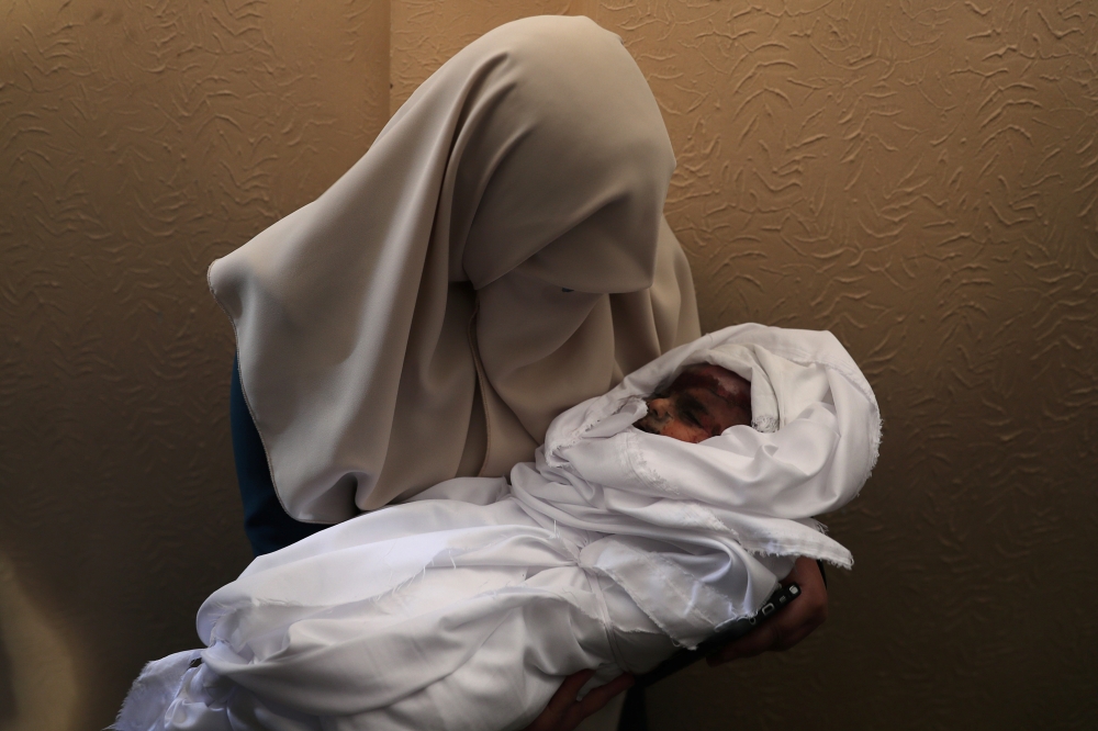 A relative carries the body of 4-month old Palestinian baby girl Maria Al-Ghazali during her funeral in Gaza City on Monday. — Reuters