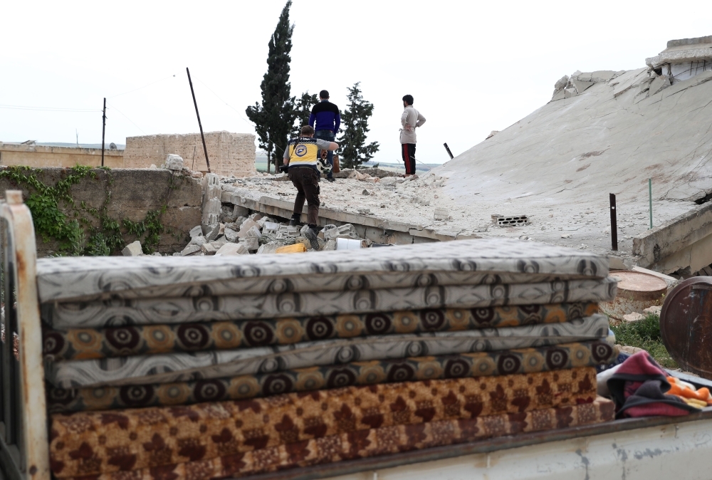 Rescuers and civilians check the rubble of a building as people prepare to leave their houses in the village of Rabaa Jour in the the militant-held Syrian province of Idlib on Monday following reported shelling and air strikes in the area. — AFP 