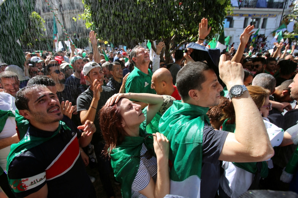 Demonstrators are sprayed with water to cool them off from the heat during a protest demanding the removal of Algeria’s ruling elite in Algiers on Friday. — Reuters