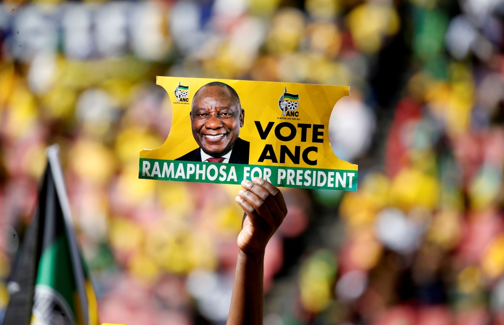 A supporter holds a placard with the face of President of South Africa's governing African National Congress Cyril Ramaphosa, during the party's final rally at Ellis Park Stadium in Johannesburg. — AFP