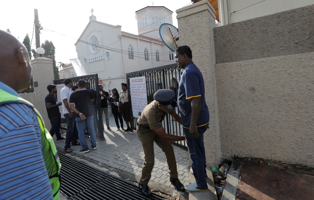 A police officer searches a worshiper at the main entrance of the St.Theresa's church in Colombo as the Catholic churches in Sri Lanka restart their Sunday service after Easter Sunday bombing attacks on 21st of April. — Reuters