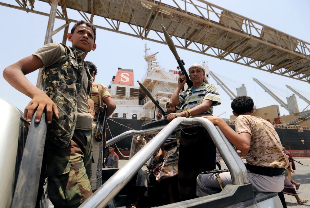 Members of the Houthi movement ride in the back of a vehicle during withdrawal from Saleef port in Hodeida province, Saturday. — Reuters