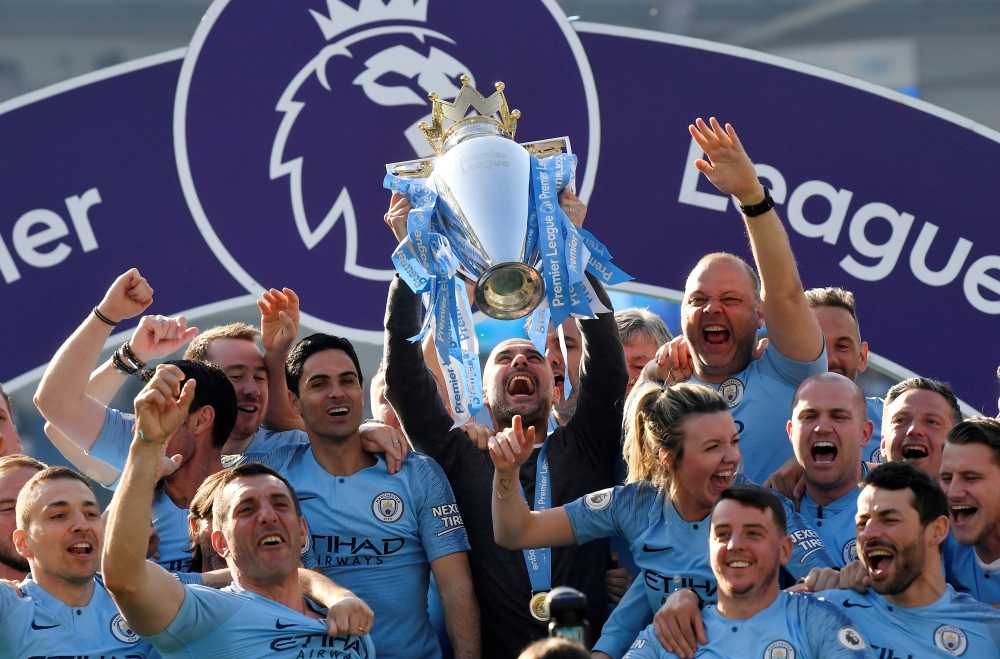 Manchester City manager Pep Guardiola lifts the trophy as they celebrate winning the Premier League with a 4-1 rout of Brighton & Hove Albion at the American Express Community Stadium, Brighton, Britain, on SUnday. — Reuters   