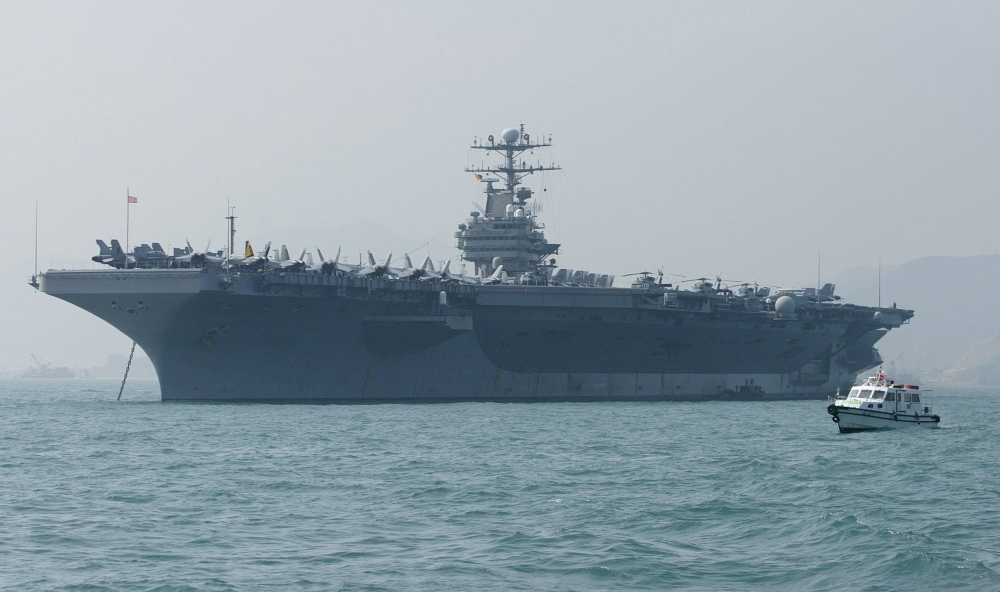 In this file photo a small boat sails by the USS Abraham Lincoln moored in Hong Kong. — AFP