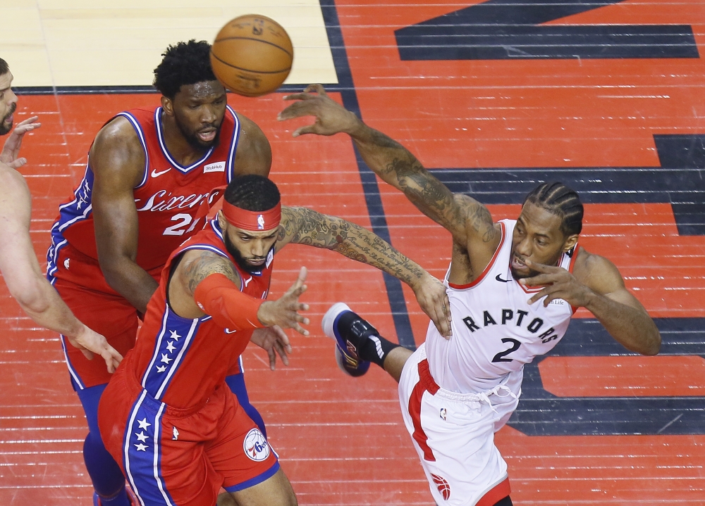 Toronto Raptors forward Kawhi Leonard (2) passes the ball over Philadelphia 76ers forward Mike Scott (1) and center Joel Embiid (21) during game seven of the second round of the 2019 NBA Playoffs at Scotiabank Arena. Toronto defeated Philadelphia. — Reuters