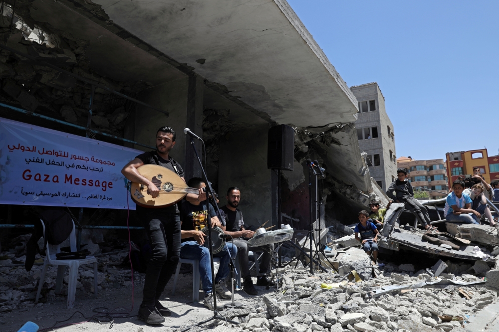 A Palestinian singer performs on Tuesday on the rubble of a building that was recently destroyed by Israeli air strikes in Gaza City during a musical event calling to boycott the Eurovision Song Contest hosted by Israel. — Reuters