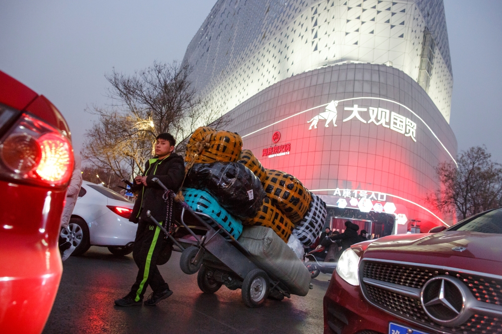 A deliveryman leans against a cart outside a wholesale market in central Zhengzhou, Henan province, China, in this file photo. — Reuters