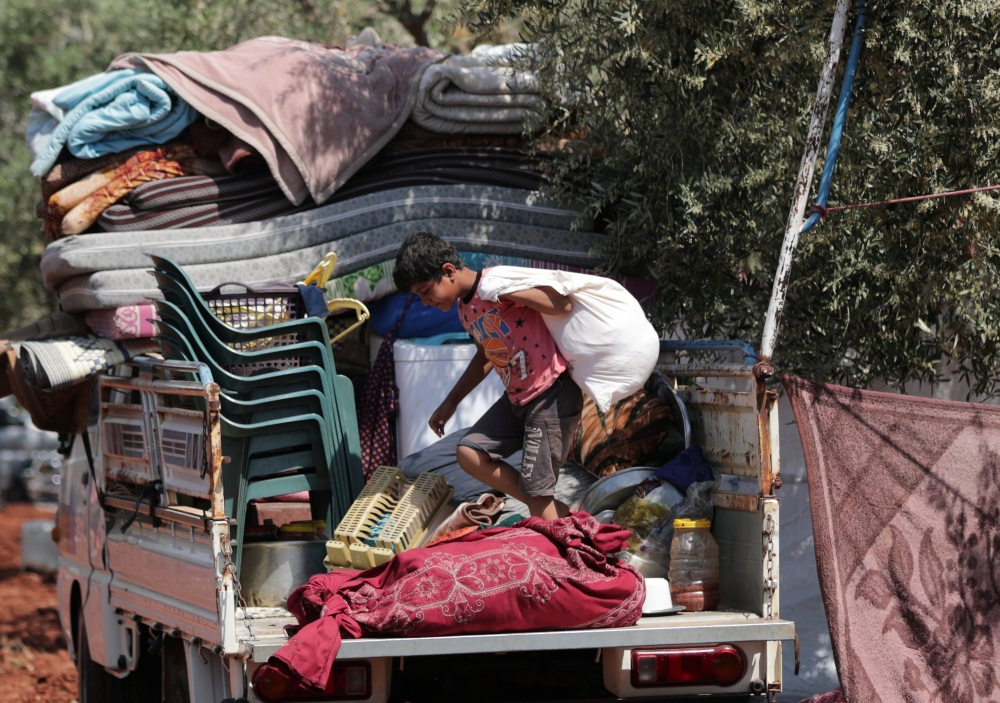 A displaced Syrian boy holds belongings at a back of a truck at Atmeh town, Idlib province, Syria, in this May 15, 2019 file photo. — Reuters